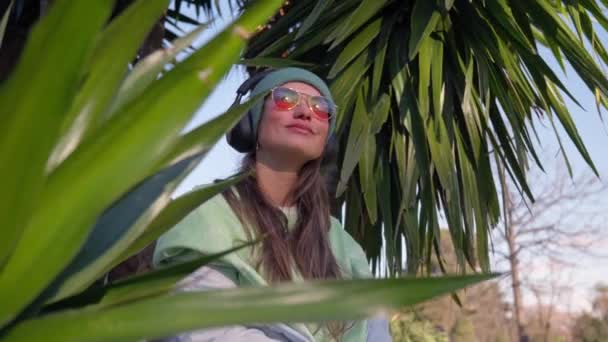 Девушка Наушниках Среди Пальмовых Листьев Высококачественные Кадры — стоковое видео