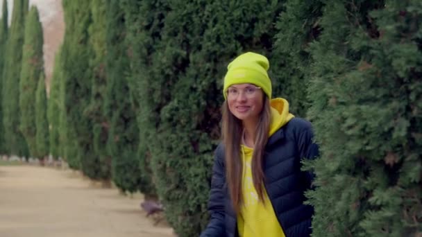 Girl Looks Out Tree Waves Her Hand Bright Hat Smile — Vídeo de stock