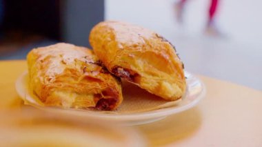 Puff pastry, chocolate rolls on the table in the cafe. Powdered sugar, chocolate cream inside a puff pastry on a plate.