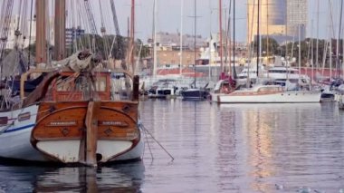 An old sailboat in the port, Barcelona at sunset. Seagulls are circling.