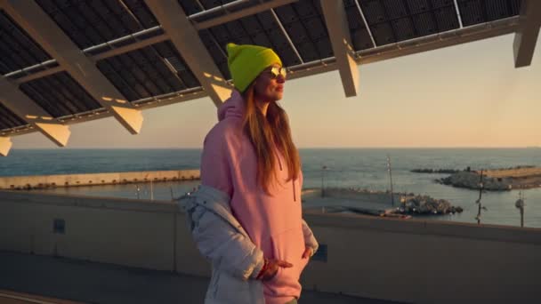 Дівчина Йде Під Дахом Будівлі Сонячними Панелями Рожева Куртка Яскравий — стокове відео