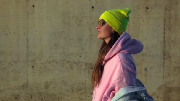 Дівчина Ходить Бетонній Стіні Яскравий Капелюх Рожева Куртка — стокове відео