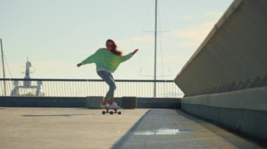 A girl rides a skateboard from afar. High quality 4k footage