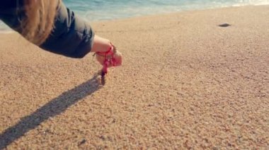 A girl draws a heart on the sand. High quality 4k footage