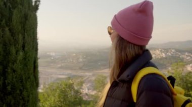 A tourist girl walks along the alley against the background of the city. High quality 4k footage