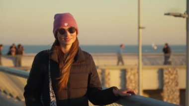 Portrait of a girl in warm clothes walking along the pier. High quality 4k footage