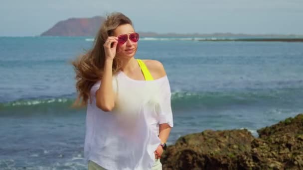 ビーチで白いTシャツの少女は 距離では 島を見ることができます 高品質4K映像 — ストック動画