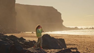 Kız denizin ve kayaların arkasında geniş bir sahil boyunca yürüyor. Yüksek kalite 4k görüntü