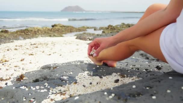 白い女の子が海の背景に座り 海岸に小さな小石に触れています 高品質4K映像 — ストック動画