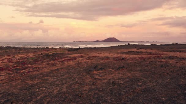 Fale Zderzają Się Kamiennym Brzegiem Oddali Widać Sylwetkę Wulkanicznej Wyspy — Wideo stockowe