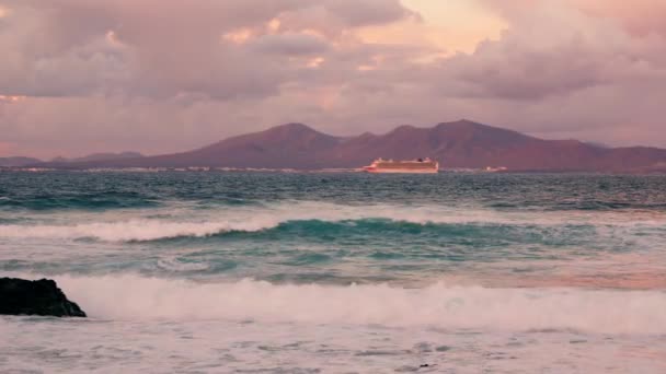 海浪冲击着岩石海岸 在远处 你可以看到一座火山岛的轮廓 高质量的4K镜头 — 图库视频影像