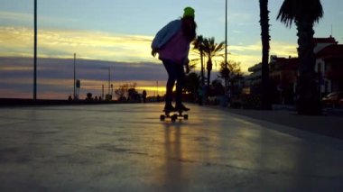 A girl rides a skateboard against the backdrop of a sunset. High quality 4k footage