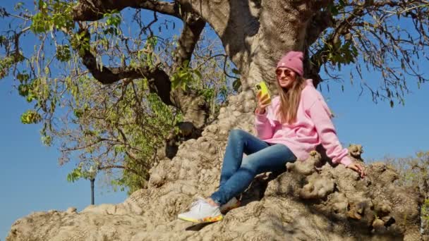 Dívka Sedí Pod Stromem Dívá Telefon Vysoce Kvalitní Záběry — Stock video