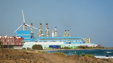 Sersemletici sahil şeridinin nefes kesen manzarasını ele alalım, yemyeşil ve deniz esintisinin gücünü kullanan yüksek rüzgar türbini
