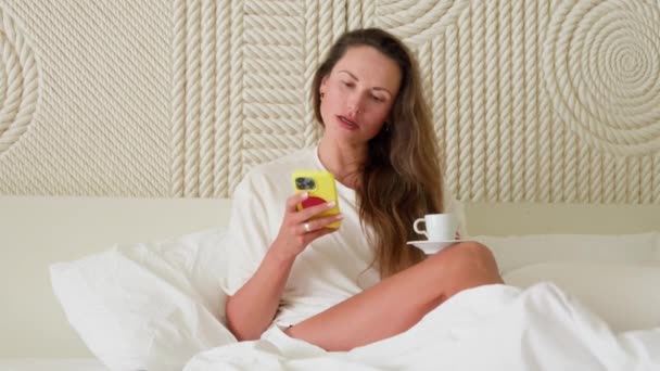 Uma Menina Mensagens Telefone Enquanto Está Deitada Cama Pela Manhã — Vídeo de Stock