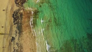Havada süzülürken, kumlu kumsalın ve berrak suların güzelliğini yakalayan çarpıcı kıyı şeridini kuşbakışı görün.