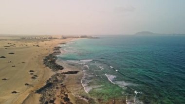 Fuerteventura 'nın yabani plajları ve kumulları boyunca keyifli bir hava yolculuğuna çıkın ve kendinizi doğal güzelliğine daldırın. Yüksek kalite 4k görüntü