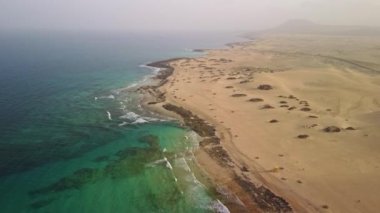 Fuerteventura 'nın güzelliğini gözler önüne seren kum tepecikleriyle bezenmiş çarpıcı kıyı şeridinin nefes kesici görüntüsünü yakalayın.