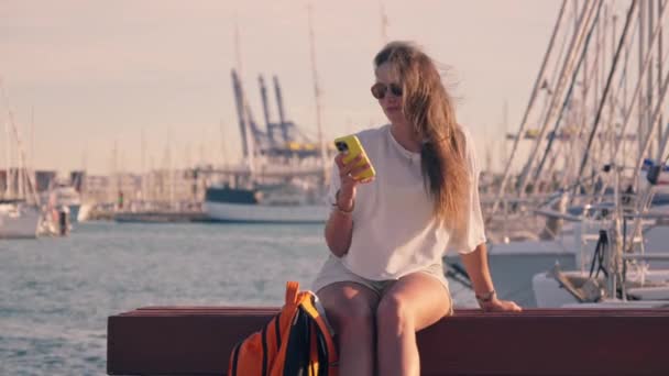 Девушка Читает Сообщения Сидя Скамейке Яхт Клубе Высококачественные Кадры — стоковое видео