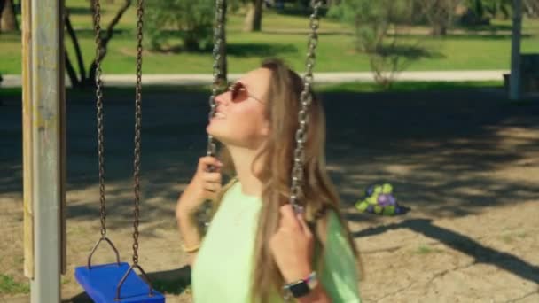 Girl Wearing Sunglasses Swings Back Forth Swing Her Hair Flowing — Stock Video