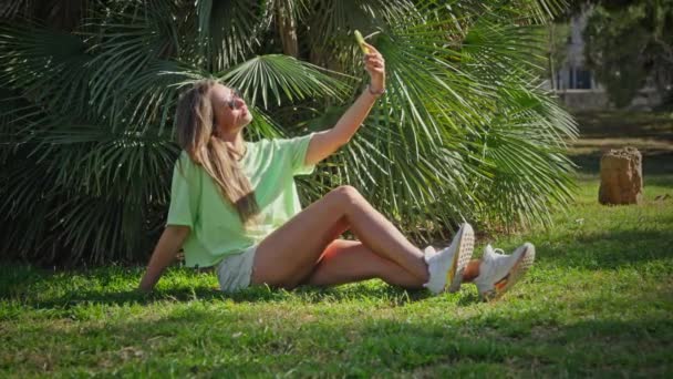 女孩在公园的棕榈树下平静地休息 四周环绕着绿色和宁静 高质量的4K镜头 — 图库视频影像
