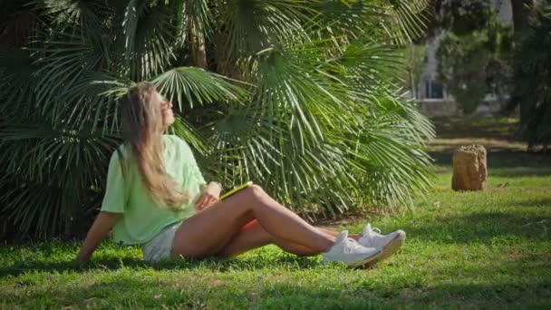 Dziewczyna Siedzi Parku Ciesząc Się Cieniem Palm Pociesza Się Spokojnym — Wideo stockowe