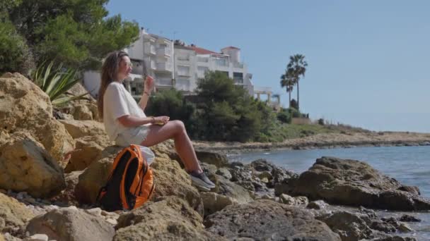 Eine Frau Sitzt Auf Einem Felsen Neben Einem Gewässer — Stockvideo