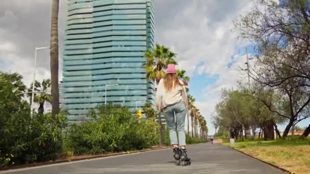 高い建物の隣の通りにスケートボードに乗っている女性 — ストック動画