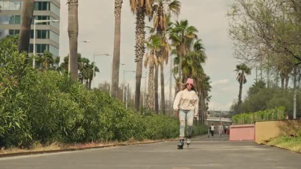 ヤシの木の隣の通りにスケートボードに乗っている男 — ストック動画