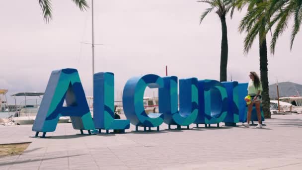 Dziewczyna Idzie Tle Dużej Inskrypcji Nazwą Miasta Alcudia Wysokiej Jakości — Wideo stockowe
