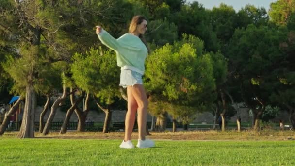 サンシャインの緑の背景から公園で回転する女の子 高品質の4K映像 — ストック動画