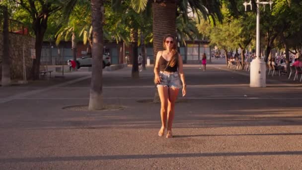 Een Vrouw Die Door Een Straat Naast Palmbomen Loopt — Stockvideo