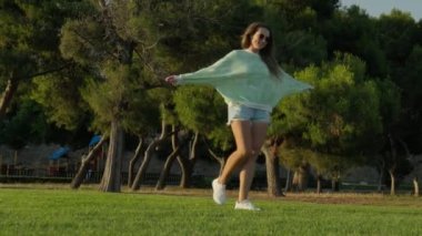 Gün batımında güzel bir parkta dönen bir kız. Yüksek kalite 4k görüntü