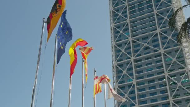 背の高い建物の前で風に飛んでいるたくさんの旗 — ストック動画