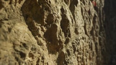 Kaya bir duvarın üzerinde yürüyen bir insan..