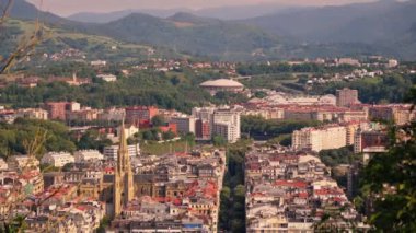 Arka planda yüksek dağlar bulunan şehir manzarası.