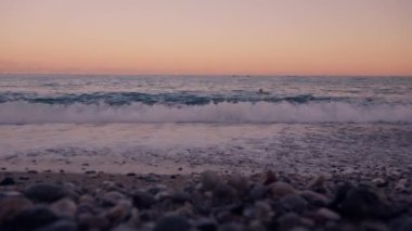 Dalgalar kayalara çarpar ve okyanus kayalık bir sahilden ufka doğru uzanır..