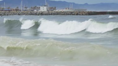 Sörf tahtasının üzerinde ustalıkla duran bir adam güçlü bir dalgaya biner..