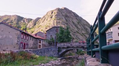 Taş köprü yüksek bir dağın yakınındaki küçük bir nehri geçiyor..