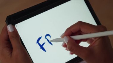 Tablet ekranına yazmak için kalem kullanan bir kişi.