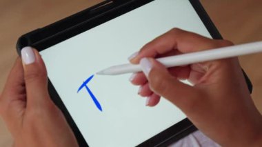 Tablet ekranında kalem kullanan bir kişi.