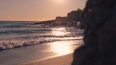 Güneş ışığı sahilin yüzeyinden yansıyor dalgalar yavaşça kıyıya çarpıyor..