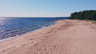 Yumuşak dalgalar sakin bir kumsala vurur. Orada altın kum, güneşle dolu parlak bir gökyüzünün altında dingin mavi suyla buluşur..