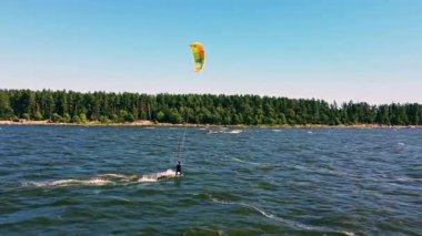 Yetenekli bir uçurtma sörfçüsü berrak mavi gökyüzünün altında canlı sularda gezinir, okyanus melteminin ve güneşin tadını çıkarır..