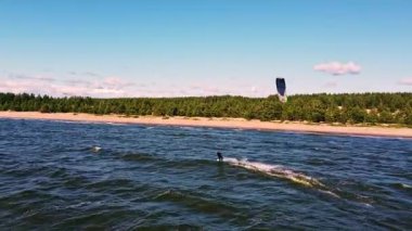 Yetenekli bir uçurtma ustası, bereketli bir orman ve kumlu kıyılarla çevrili parlak bir gökyüzü altında parıldayan dalgaları keser ve yazları neşe içinde yakalar..