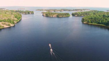 Two boats navigate the calm waters of a picturesque lake surrounded by lush green islands under a clear blue sky.