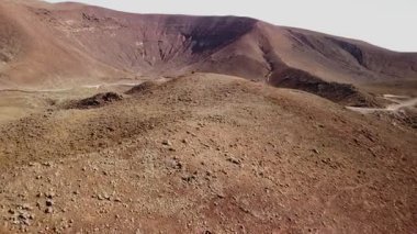 Uçsuz bucaksız bir çöl manzarası, berrak bir gökyüzü altında yuvarlanan tepeler ve kayalık arazi ile sergileniyor, sakin bir ortamda saf güzellikler sergileniyor..