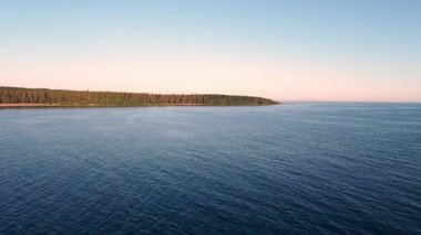 Sakin dalgalar ufuk boyunca uzanan sakin bir orman gibi yavaşça kıyıya doğru süzülüyor alacakaranlık ışığı altında..