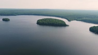 Durgun sular, yeşil adaların engin orman manzaralarıyla çevrili sakin bir göle dönüşmesiyle sabah ışığını yansıtıyor..