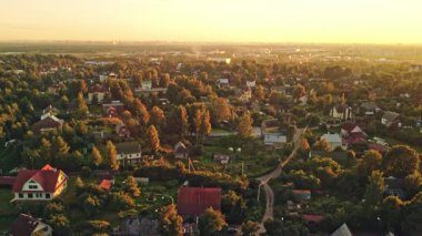 Altın güneş ışığı, yemyeşil ve konforlu evlerle dolu sakin bir köyü aydınlatıyor ve güzel bir akşam ortamı yaratıyor..